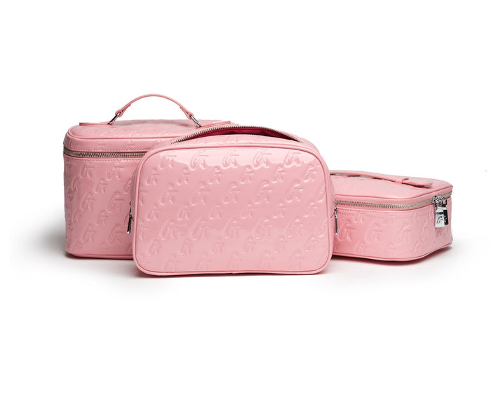Pink monogram toiletry bags with embossed logo pattern, including a mirror bag, all with silver zippers.