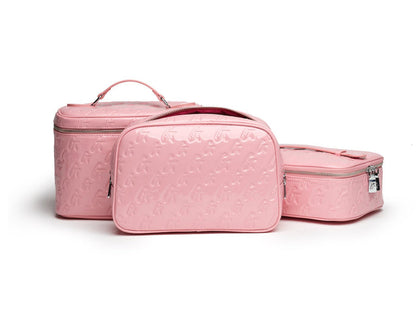 Pink monogram toiletry bags with embossed logo pattern, including a mirror bag, all with silver zippers.