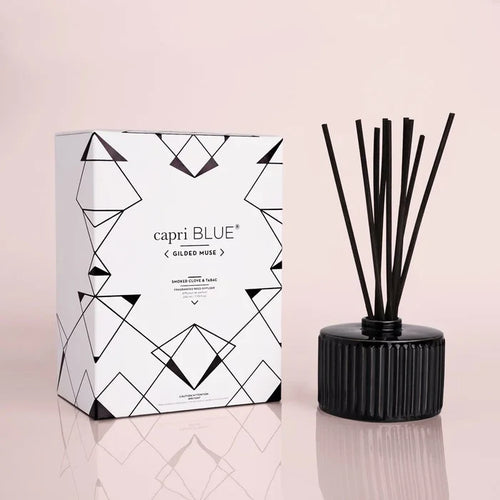A black reed diffuser with a geometric patterned box in the background, labeled 'capri BLUE'.