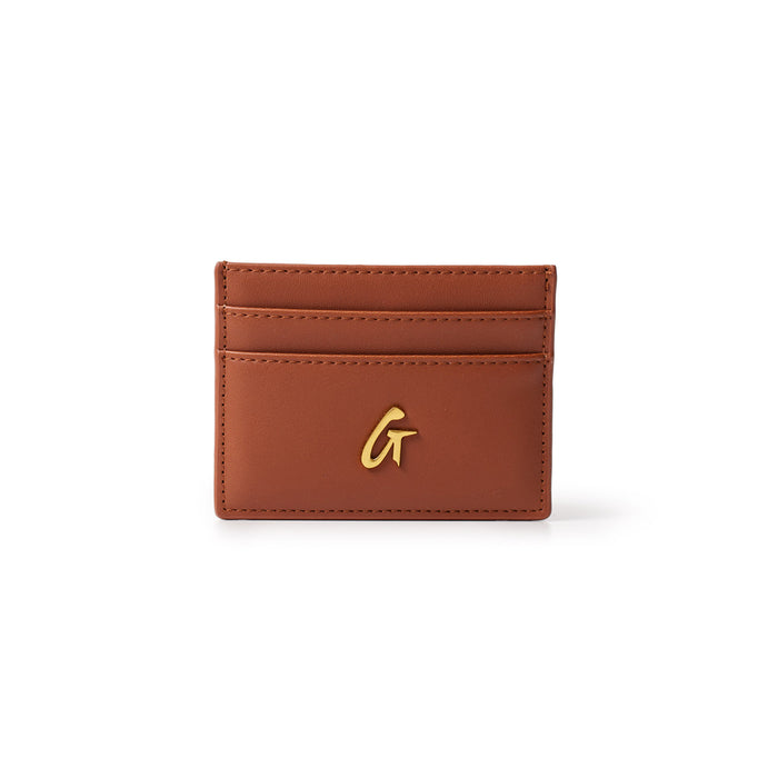 Brown leather gold card holder with a gold "G" logo on the front, featuring multiple card slots on a white background.