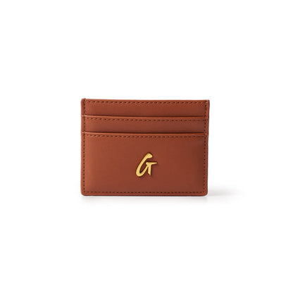 Brown leather gold card holder with a gold "G" logo on the front, featuring multiple card slots on a white background.