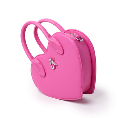 Pink heart-shaped bag with handles, silver logo, and zipper closure, designed for a stylish and playful accessory.