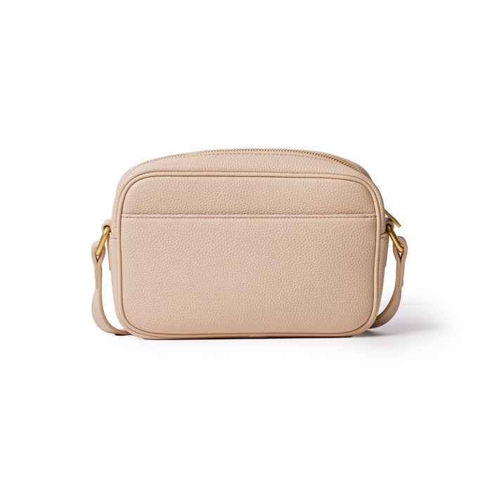 Nude-colored Pebble Camera Bag with a textured surface, gold hardware, and adjustable strap, ideal for carrying camera gear.