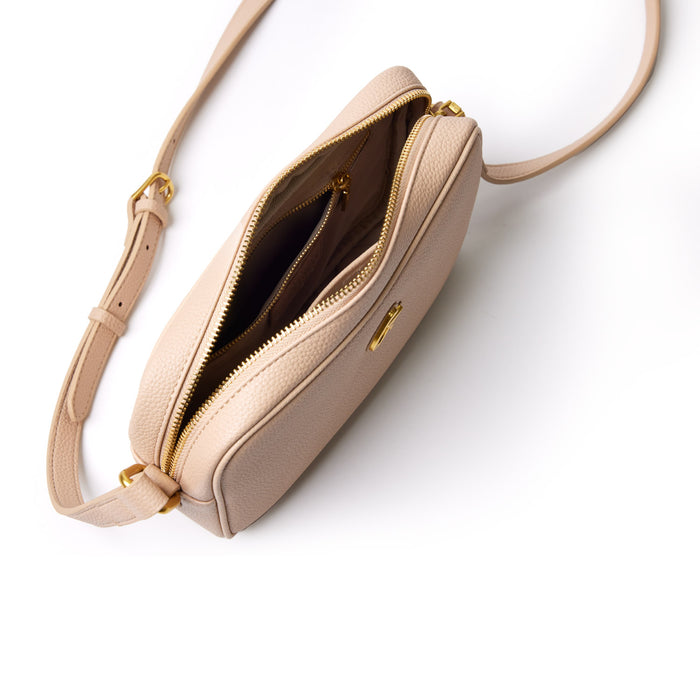 Nude pebble leather camera bag with gold zipper and adjustable strap, open to show interior compartments.