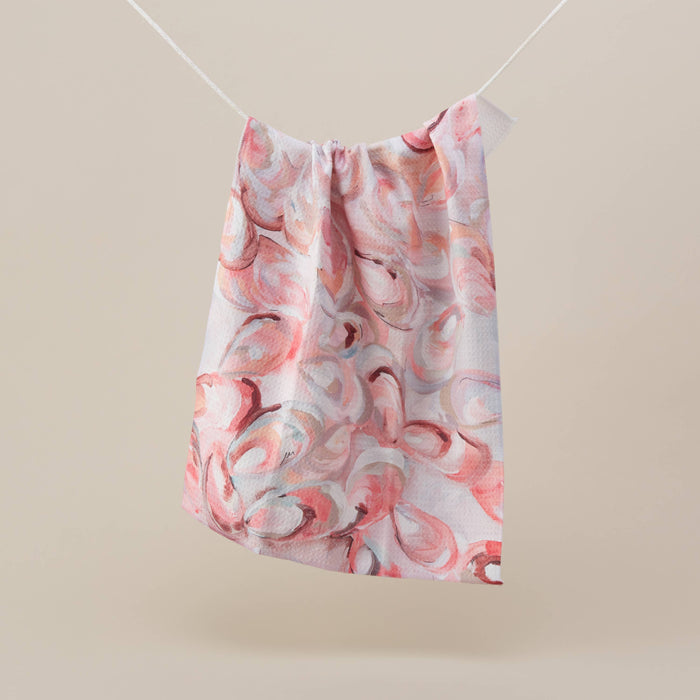 Kitchen tea towel with an oyster print hanging on a white tag, displayed on a plain background.