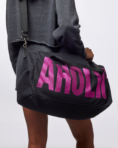 Black canvas duffle bag featuring bold pink "AHOLIC" lettering, ideal for stylish travel and everyday use.