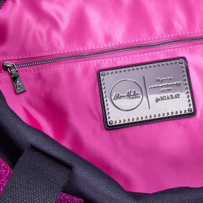 Interior view of the black and pink canvas duffle bag featuring a shiny pink lining and a branded metal tag.