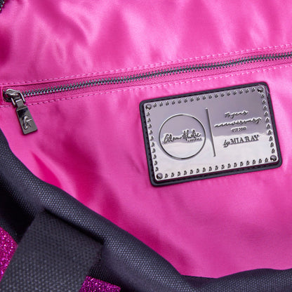Interior view of the black and pink canvas duffle bag featuring a shiny pink lining and a branded metal tag.