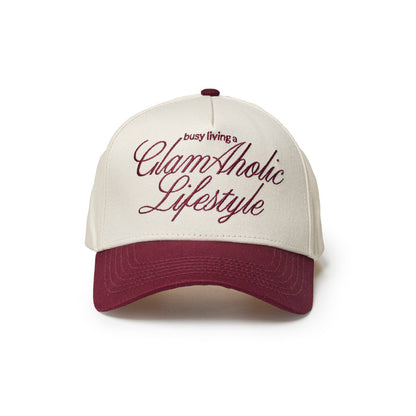 Burgundy trucker hat with white front panel and embroidered "busy living a GlamAholic Lifestyle" text.