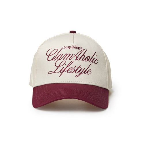 Burgundy trucker hat with white front panel and embroidered "busy living a GlamAholic Lifestyle" text.