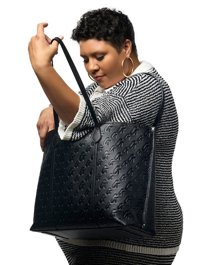 Model showcasing the XL Monogram Sleek Tote in black, featuring a stylish embossed design and spacious interior.