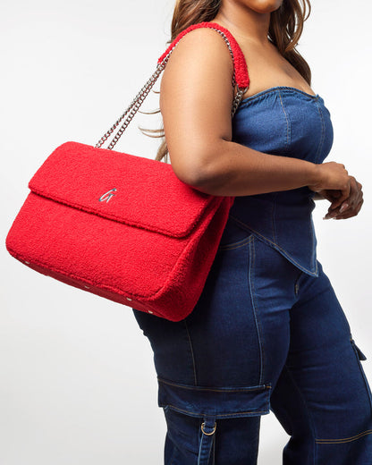 Red XL Teddy Flap Bag with a plush texture and chain strap, styled with a denim outfit for a chic look.