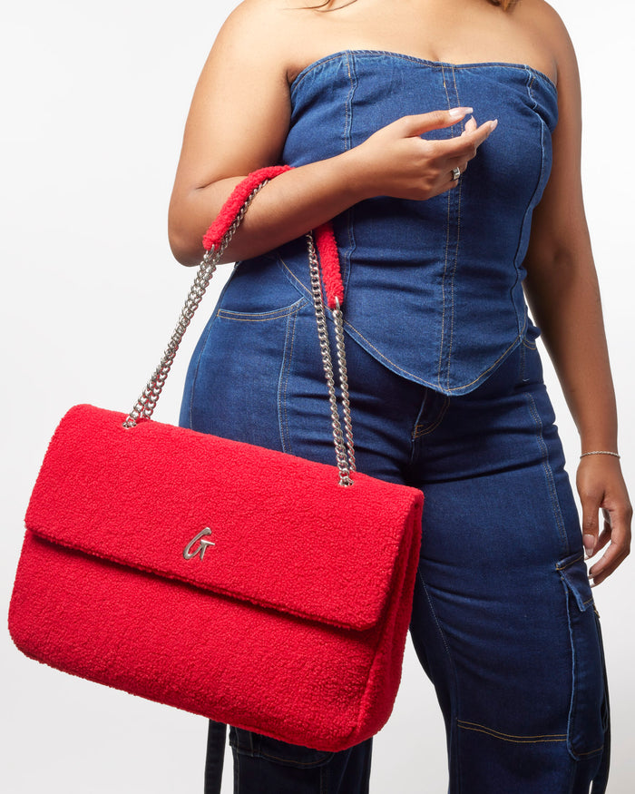 XL Teddy Flap Bag in red, featuring a plush texture and chain strap, styled with a denim outfit.